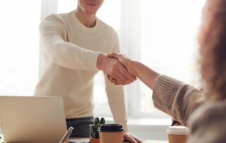 A man and a woman shaking hands in agreement, representing successful negotiation strategies
